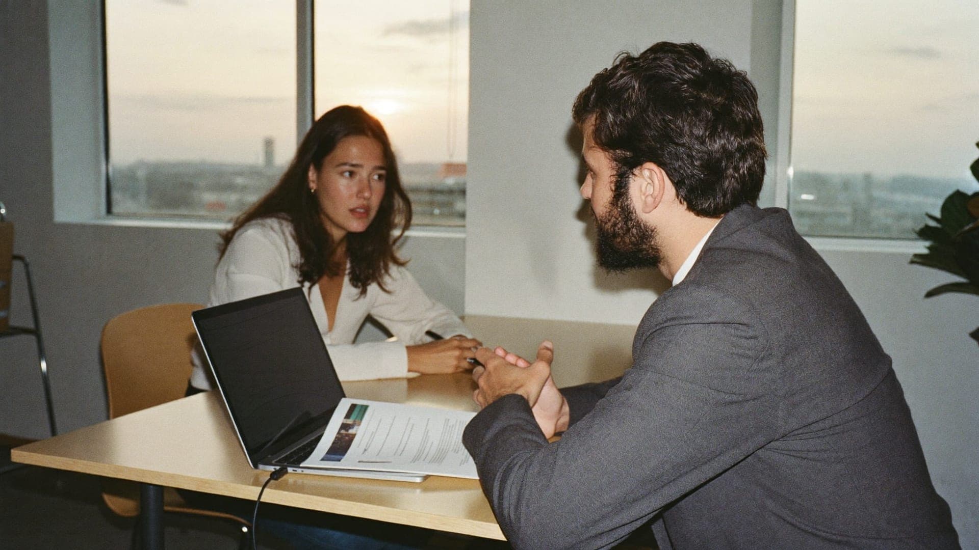 Internationale Bewerberin im Bewerbungsgespräch mit einem Recruiter, Lebenslauf und Laptop auf dem Tisch